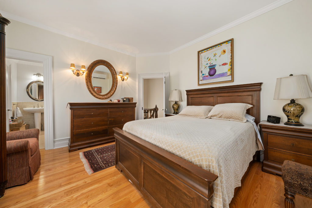 A bedroom is shown with a large bed, bulky dresser, and nightstands.